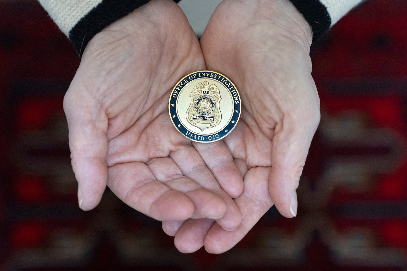 Cathy Votaw, 69, holds a coin from the USAID Office of Investigations, Thursday, Feb. 27, 2025, in Washington. (AP Photo/Jacquelyn Martin)