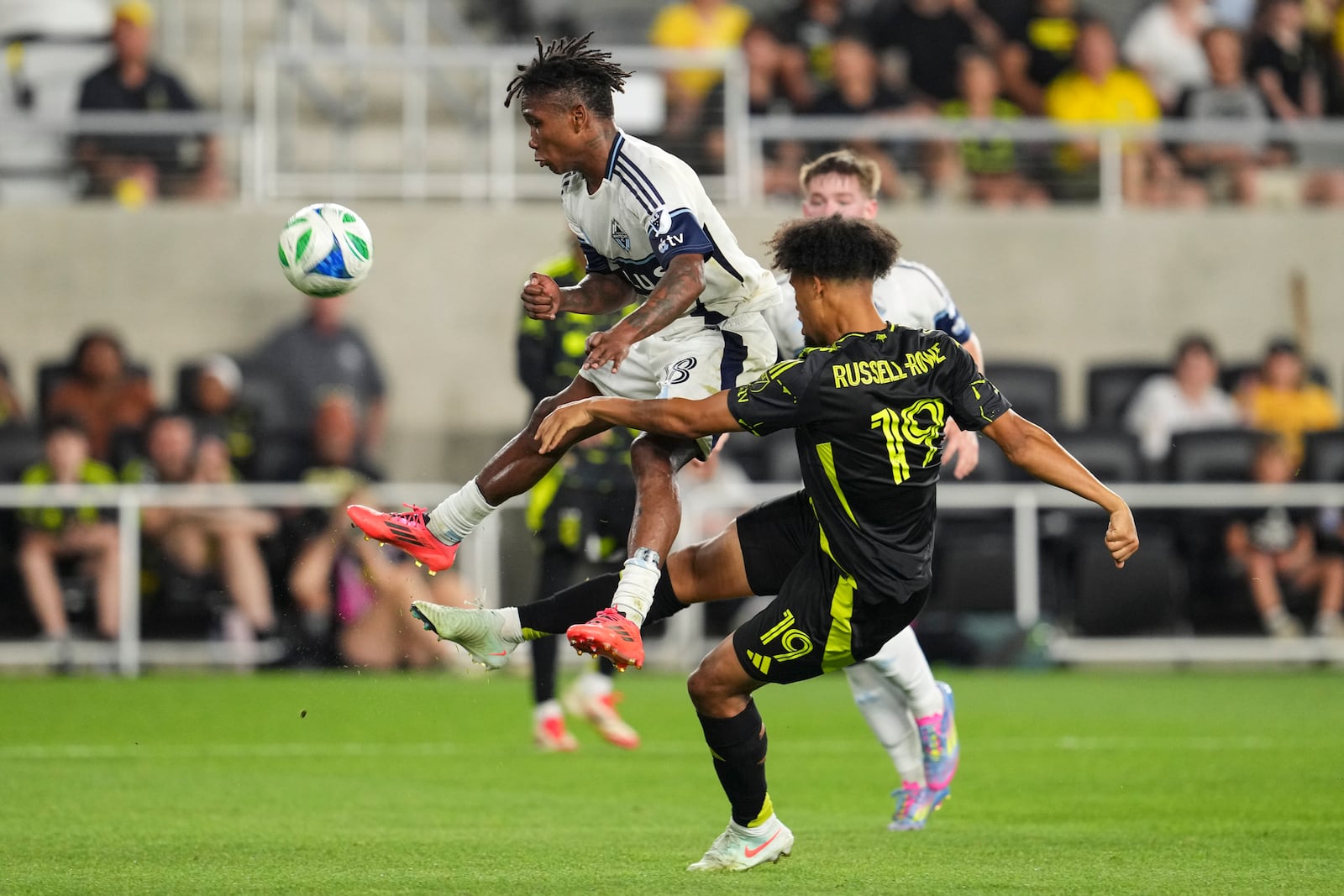Columbus Crew forward Jacen Russell-Rowe (19) shoots against Vancouver Whitecaps defender Édier Ocampo, left, during the second half of an MLS soccer match Saturday, June 14, 2025, in Columbus, Ohio. (AP Photo/Jeff Dean)