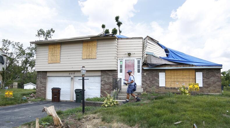 Postal worker James Goodboe delivers mail in Trotwood where many tornado damaged homes await insurance settlements or structural engineer inspections before repairs begin. Many home owners have stopped delivery as they wait for repairs. TY GREENLEES / STAFF