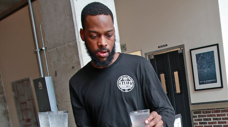 Demetrius Jones, a waiter at Charlo's Provisions & Eatery in downtown Springfield, delivers drinks to a table Wednesday, August 7, 2024. BILL LACKEY/STAFF