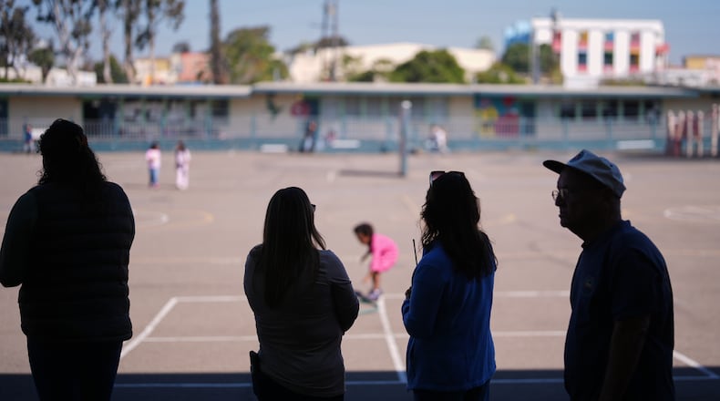 Teachers look on as students play on the playground at Perkins K-8 School Thursday, Nov. 13, 2025, in San Diego. (AP Photo/Gregory Bull)