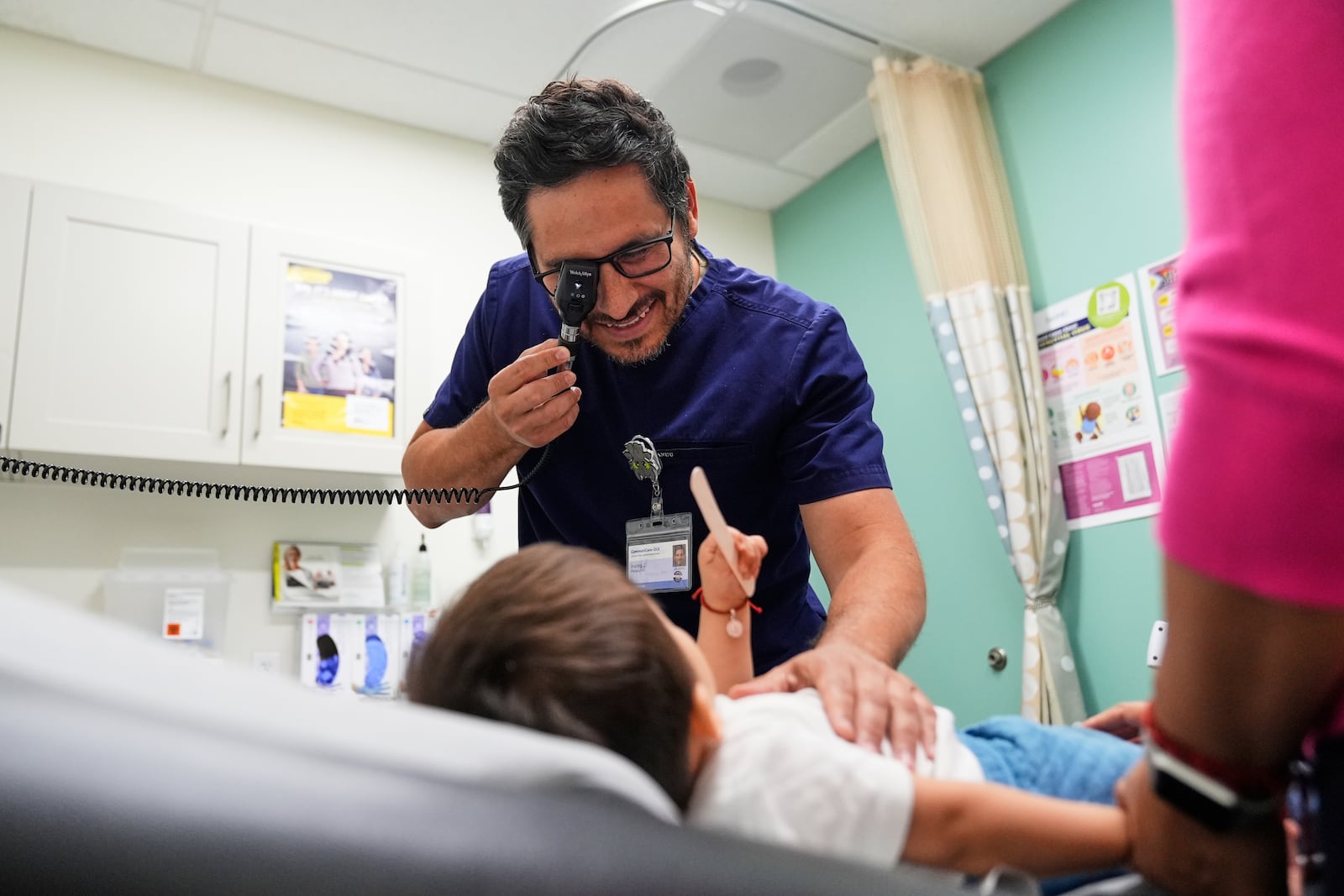 Pediatrician Irving Phillips, left, examines a 16-month-old boy at a CommuniCARE+OLE clinic Thursday, June 26, 2025, in Davis, Calif. (AP Photo/Godofredo A. Vásquez)