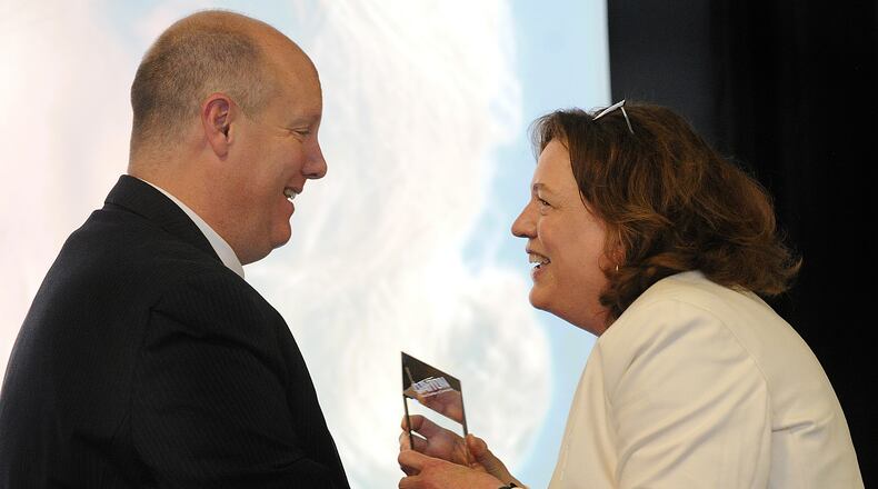 Chris Kershner hands Jana Collier, retired publisher of Cox First Media, the Dayton chamber's "Phillip Parker volunteer of the year" award at the Dayton Area Chamber 117th annual membership meeting Thursday, May 4, 2023. MARSHALL GORBY\STAFF