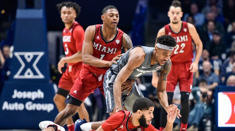 Miami’s Darrian Ringo (12) and Xavier’s Paul Scruggs (1) battle for the ball on the ground during their basketball game Wednesday, Nov. 28, 2018, at Xavier’s Cintas Center in Cincinnati. NICK GRAHAM/STAFF