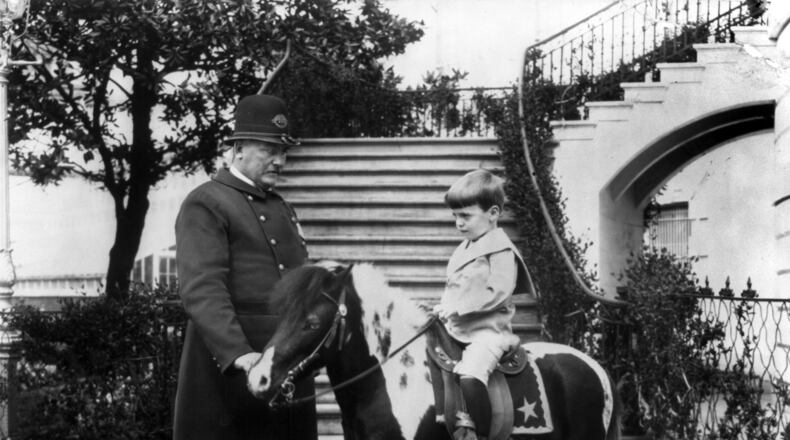 Quentin Roosevelt, son of President Theodore Roosevelt, rides his pony, accompanied by a police officer assigned to the White House, ca. 1902.
