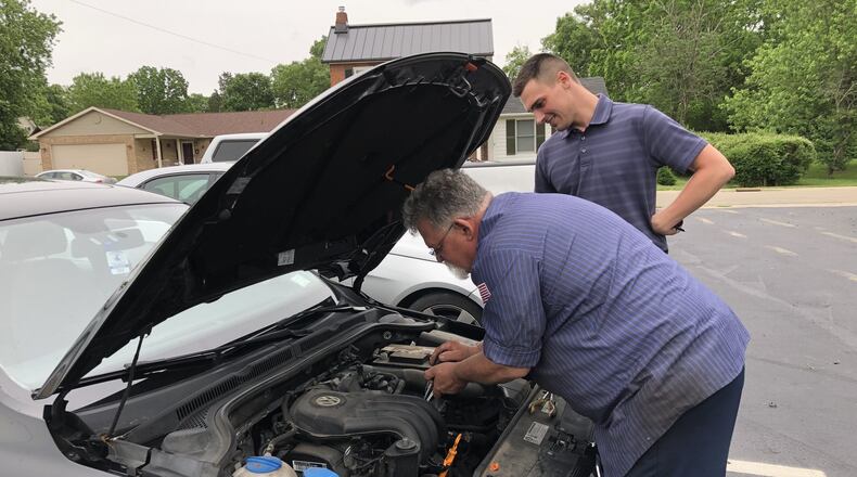 Owner Taylor Sutton , in the background, consults with mechanic Terry Johnson in the parking lot of Pro Automotive in Springboro.STAFF/LAWRENCE BUDD