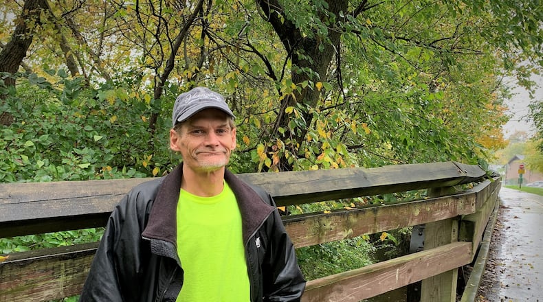 Mike Hunter stands the side of a wooden bridge on a bike path in the city of Xenia, where he once used Narcan to save a person's life.