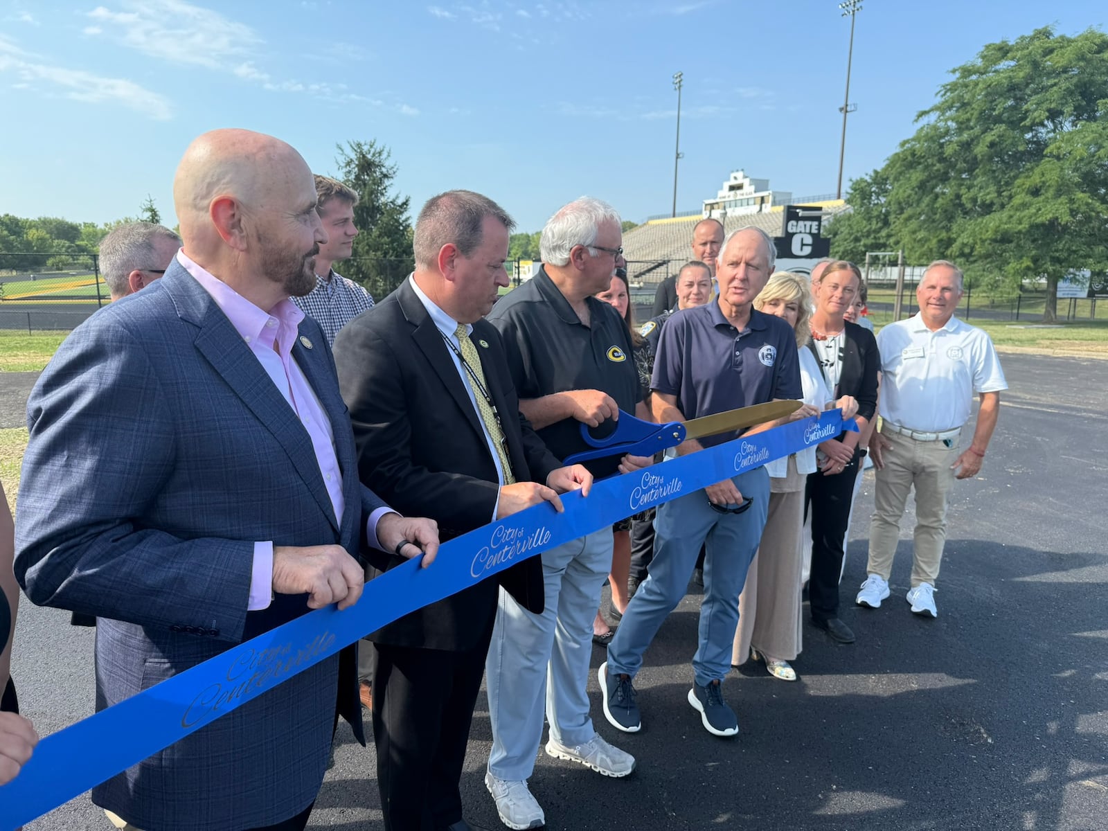State Rep. Tom Young, R-Washington Twp., Centerville Superintendent Jon Wesney, Centerville School Board President David Roer and Centerville Mayor Brooks Compton get ready to cut the ribbon on the Dimco Way extension Monday, Aug. 11, 2025. The road was extended approximately 2,000 feet from South Suburban Road near Clyo Road to Centerville High School to help reduce traffic congestion and improve roadway access. CONTRIBUTED