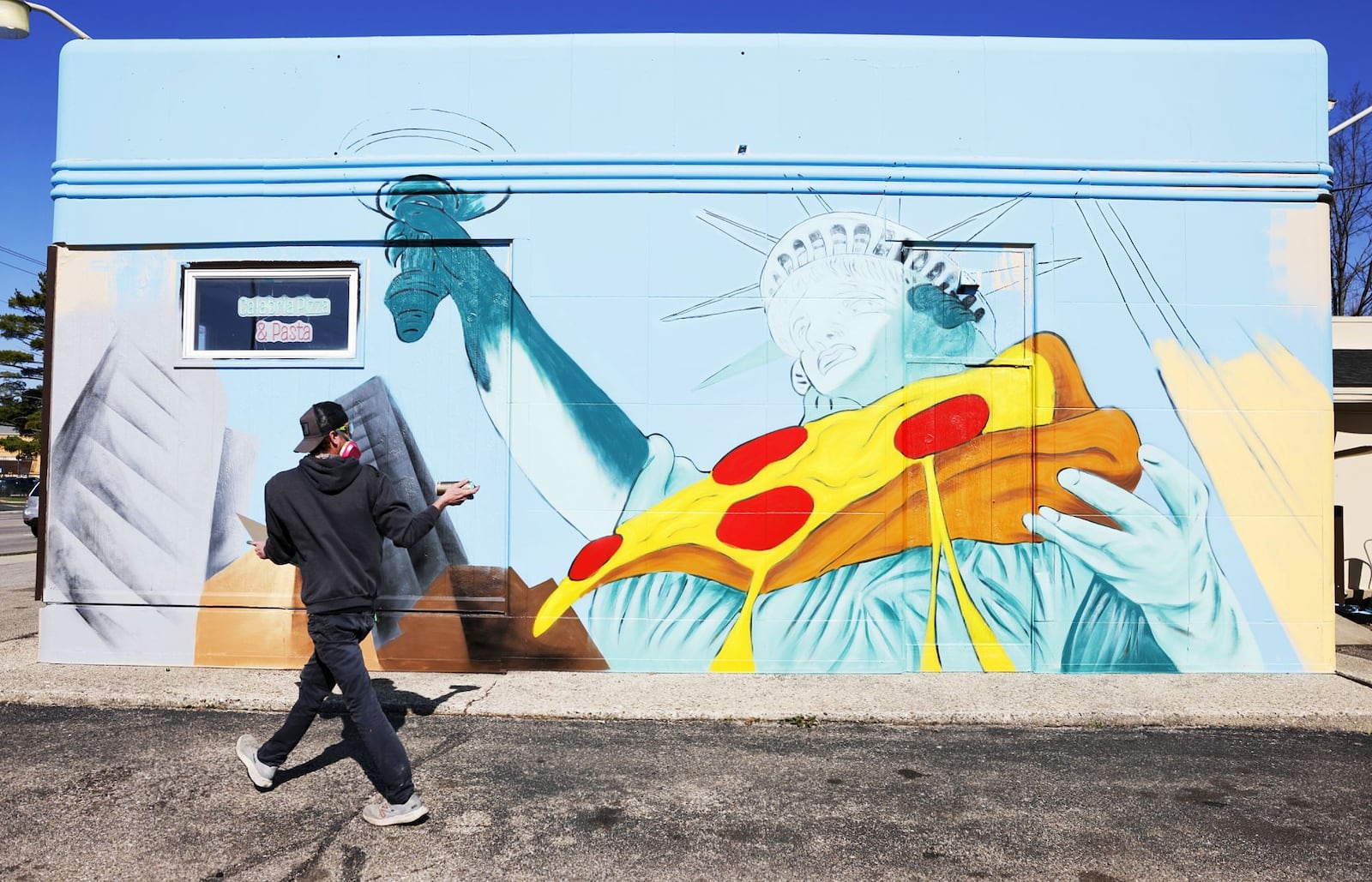 Brian Beck works on a wall mural outside Calabria Pizza Monday, March 24, 2025 on Main Street in Hamilton. NICK GRAHAM/STAFF