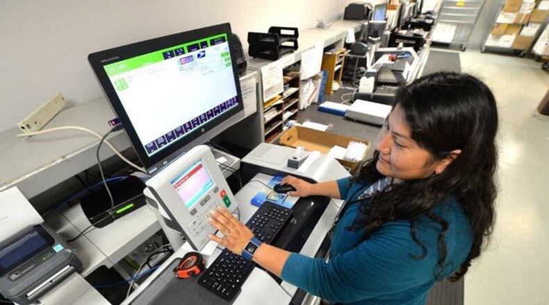 Gloria Countryman, 88th Communication Squadron Official Mail Center clerk, weighs and applies postage for outgoing mail at Wright-Patterson Air Force Base in this 2017 photo. (U.S. Air Force photo/Al Bright)
