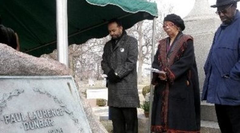 Mitchell Capel, an interpreter from Pinehurst, NC, LaVerne Sci, site manager of the Dunbar House and Hutson Tigner, a Dunbar House employee, say a prayer at the gravesite of poet Paul Laurence Dunbar.
