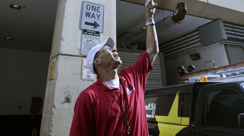 Dayton city garage maintenance worker Kevin Price points upward at the 130 W Second St./ 1st National Plaza in downtown Dayton in this 2001 photo. FILE