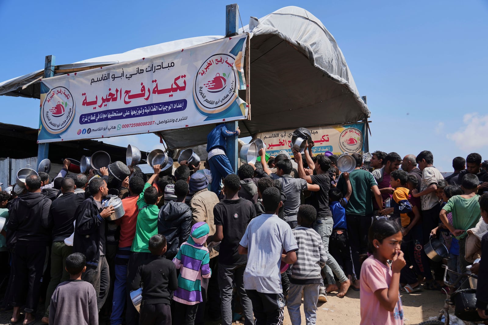 Palestinians struggle to get donated food at a community kitchen in Khan Younis, Gaza Strip, Monday, May 5, 2025. (AP Photo/Abdel Kareem Hana)