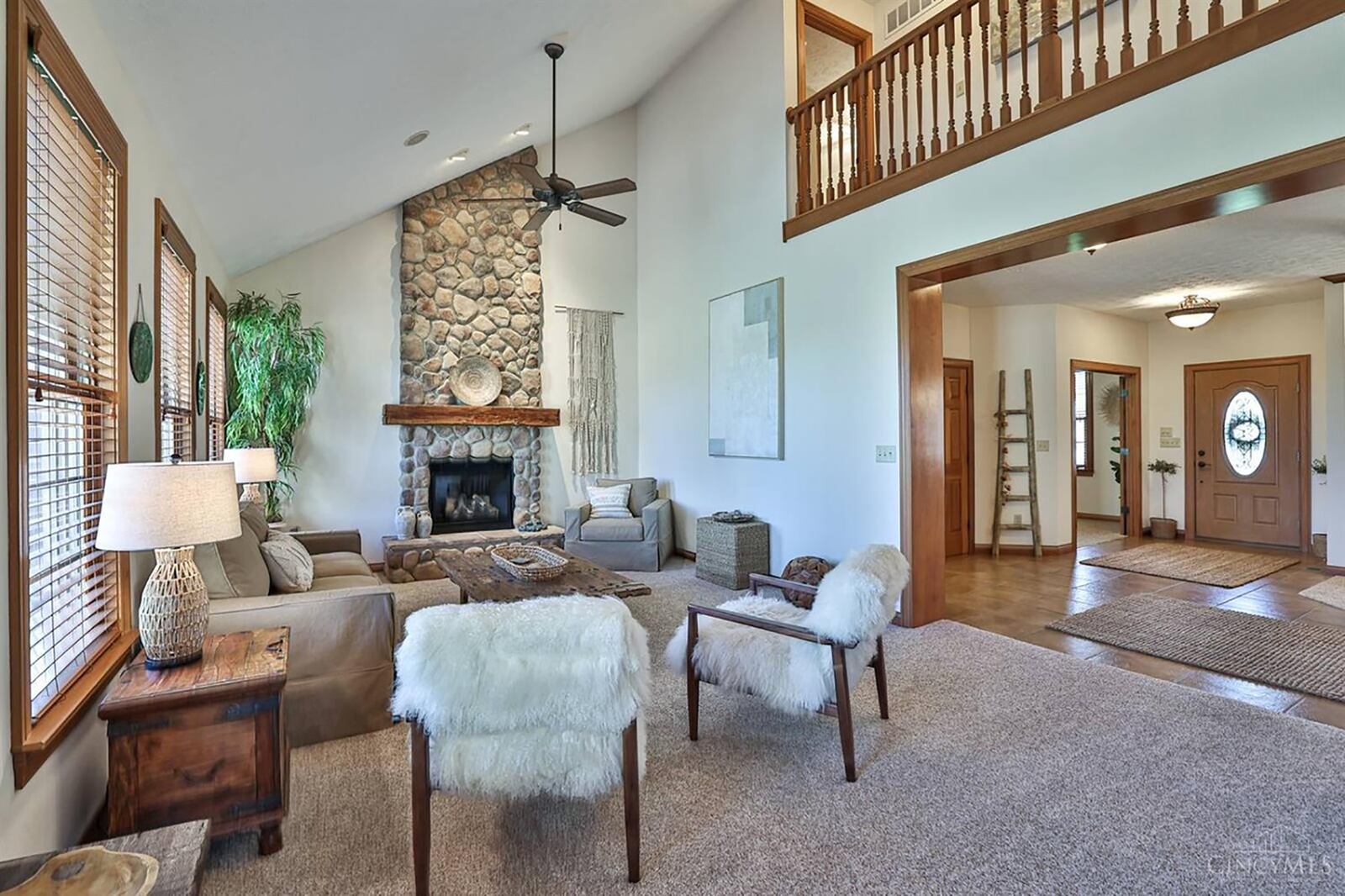 The living room has a vaulted ceiling, ceiling fan, carpeting and a river rock gas fireplace.
