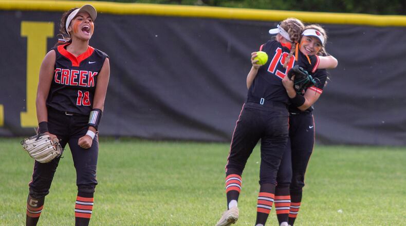 Beavercreek's Alyssa Lewis (18) shouts to her teammates while center fielder Kate Schell (19) hugs right fielder Ashley Norris after Norris ran down a hard-hit line drive for the final out of the Beavers' 5-4 victory over Western Brown in a Division I region semifinal at Centerville High School. Jeff Gilbert/CONTRIBUTED
