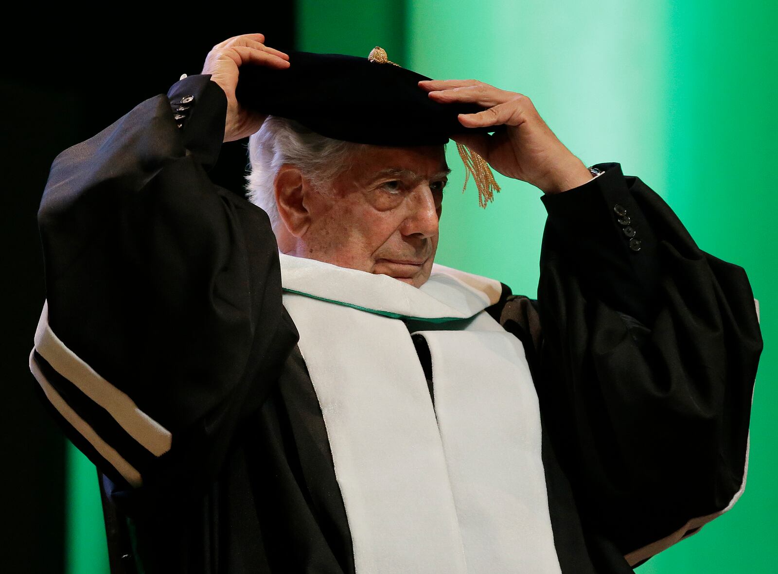 FILE - Peru's Nobel Literature Prize laureate Mario Vargas Llosa rearranges his hat during ceremonies for his conferment of the degree of Doctor of Literature, Honoris Causa, at the De La Salle University in Manila, Philippines, Nov. 8, 2016. (AP Photo/Aaron Favila, File)
