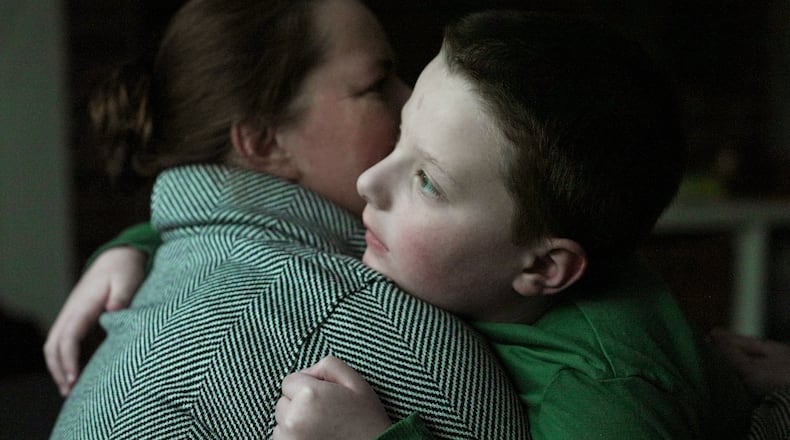 Ronan Murphy hugs his mother, Andrea, while looking at the snow falling outside their home in Ayer, Mass., on Saturday, Jan. 17, 2026. (AP Photo/Shelby Lum)