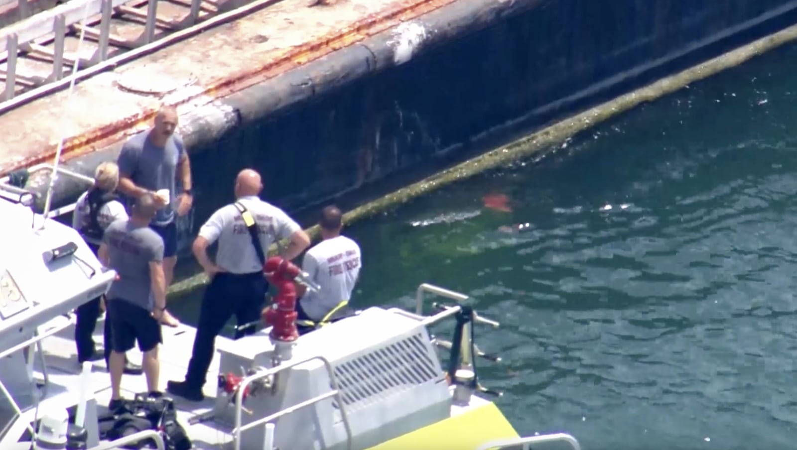 This image taken from video provided by WSVN-TV shows Miami-Dade Fire Rescue and others in a boat around what appears to be a barge involved in an accident with a group of kids and an adult on a sailing boat during a sailing camp, Monday, July 28, 2025, in Miami. (WSVN-TV via AP)