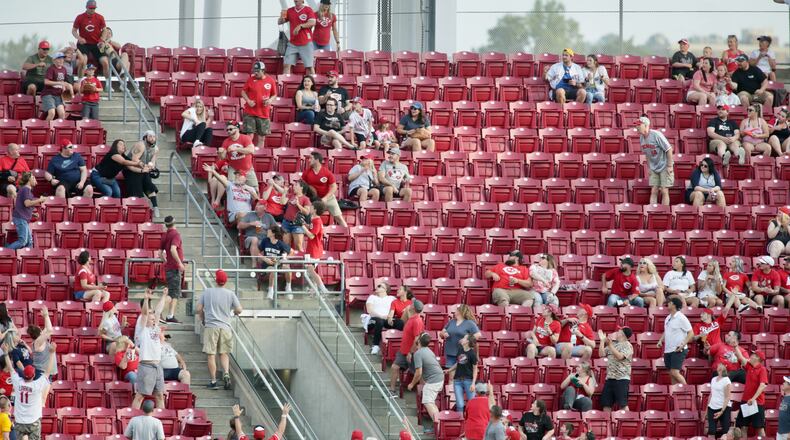 A fan tries to catch a three-run home run hit by Tyler Naquin, of the Reds, against the Brewers in the first inning on Friday, May 21, 2021, at Great American Ball Park in Cincinnati. David Jablonski/FILE