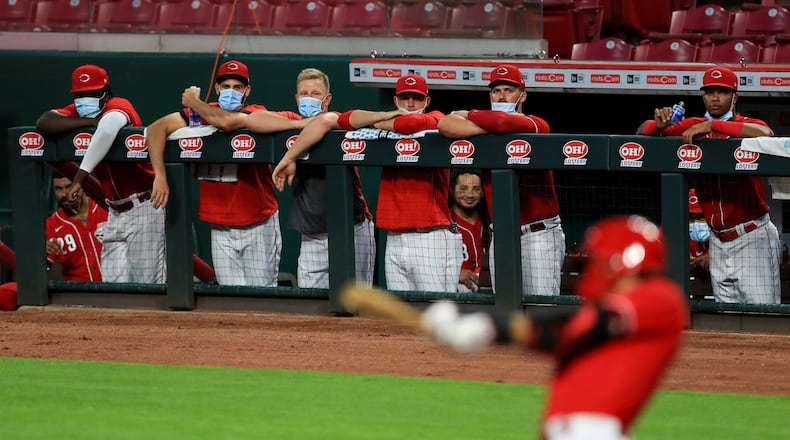 Members of the Cincinnati Reds wear masks as they watch the game from the dugout during an exhibition baseball game against the Detroit Tigers at Great American Ballpark in Cincinnati, Tuesday, July 21, 2020. The Reds won 9-7. (AP Photo/Aaron Doster)