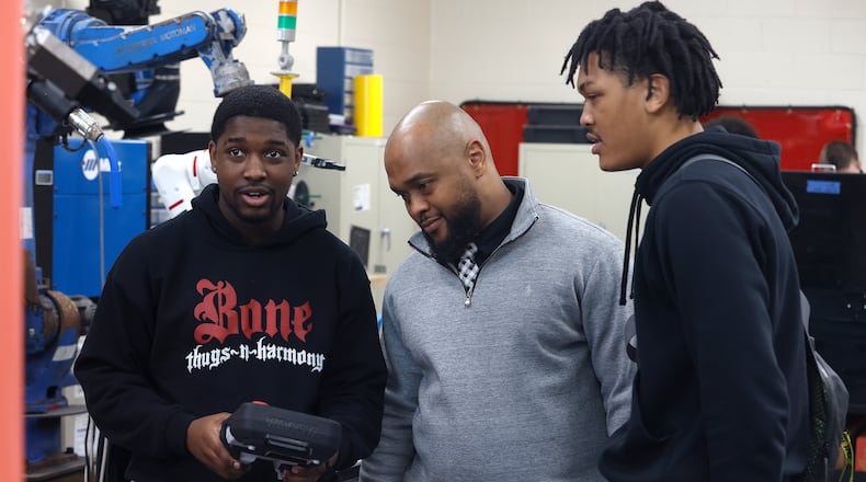 Meadowdale Career Tech Center senior Amirr Landers, left, talks to Meadowdale principal Eddie Davis, center, and fellow student Christopher Morgan about the robotics arm he and Landers are working on. MARSHALL GORBY\STAFF