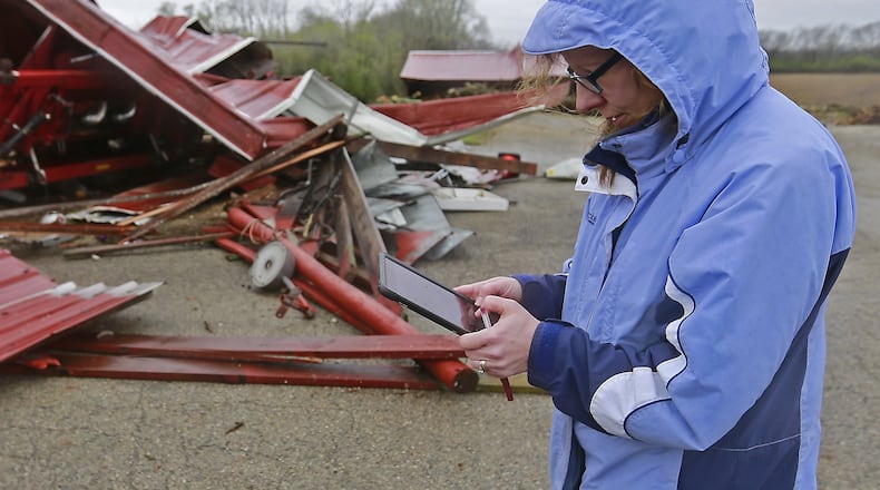 Julie Reed, from the National Weather Service, takes notes as she surveys they damage to a barn in Enon Thursday. Bill Lackey/Staff