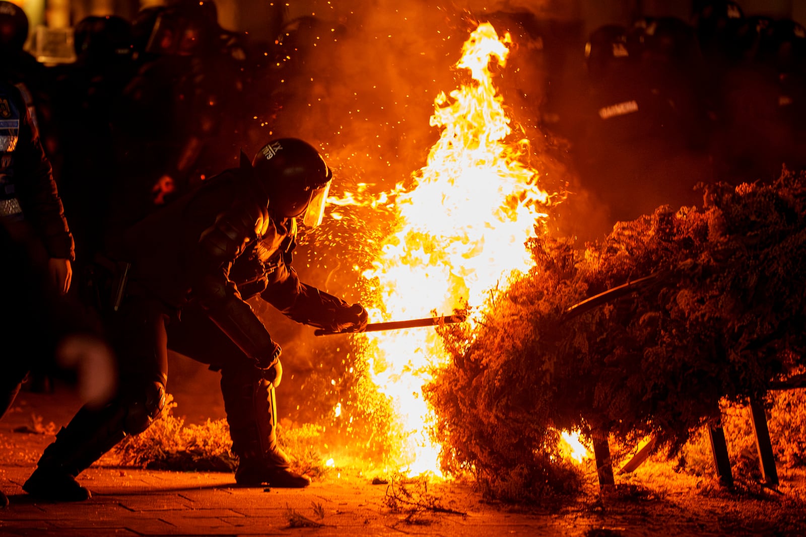 FILE- A riot policeman attempts to extinguish a fire as supporters of Calin Georgescu protested the electoral body's decision to reject his candidacy in a presidential election redo in Bucharest, Romania, Sunday, March 9, 2025. (AP Photo/Vadim Ghirda, File)