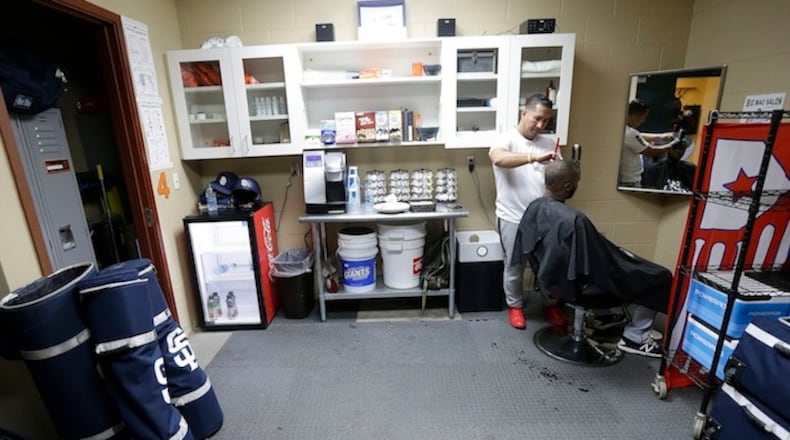 In this July 23, 2017, photo, Oscar Mamber cuts the hair of San Diego Padres center fielder Manuel Margot before a baseball game between the San Francisco Giants and the Padres in San Francisco. Mamber has been nicknamed "Crazy Barber" because he travels around the league and even turned up at the All-Star game in Miami to get everybody looking their best for baseball's summer classic. (AP Photo/Jeff Chiu)
