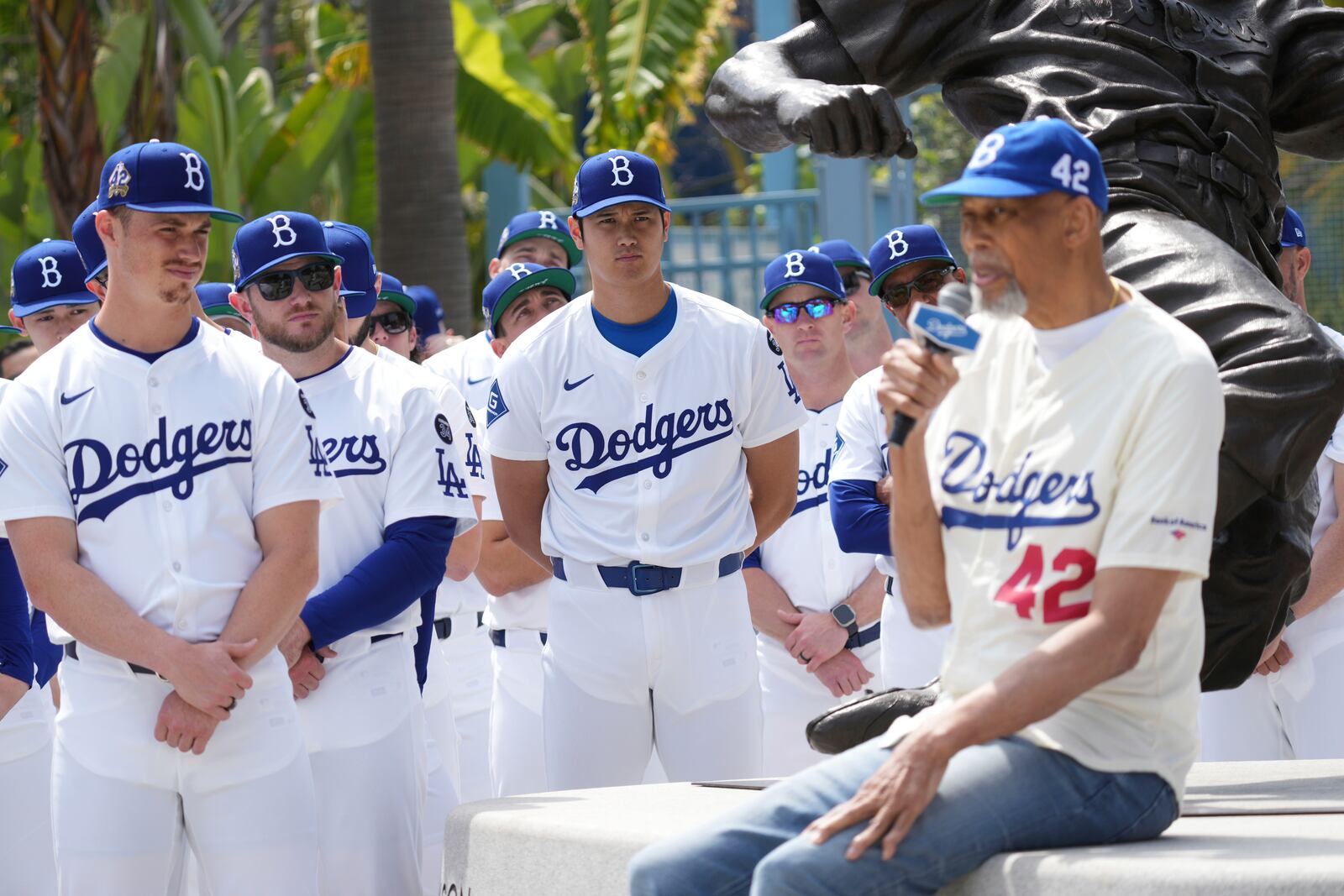 Los Angeles Dodgers' Shohei Ohtani, center, and teammates listen to former NBA player Kareem Abdul-Jabbar during an event to commemorate Jackie Robinson Day before a baseball game against the Colorado Rockies Tuesday, April 15, 2025, in Los Angeles. (AP Photo/Damian Dovarganes)