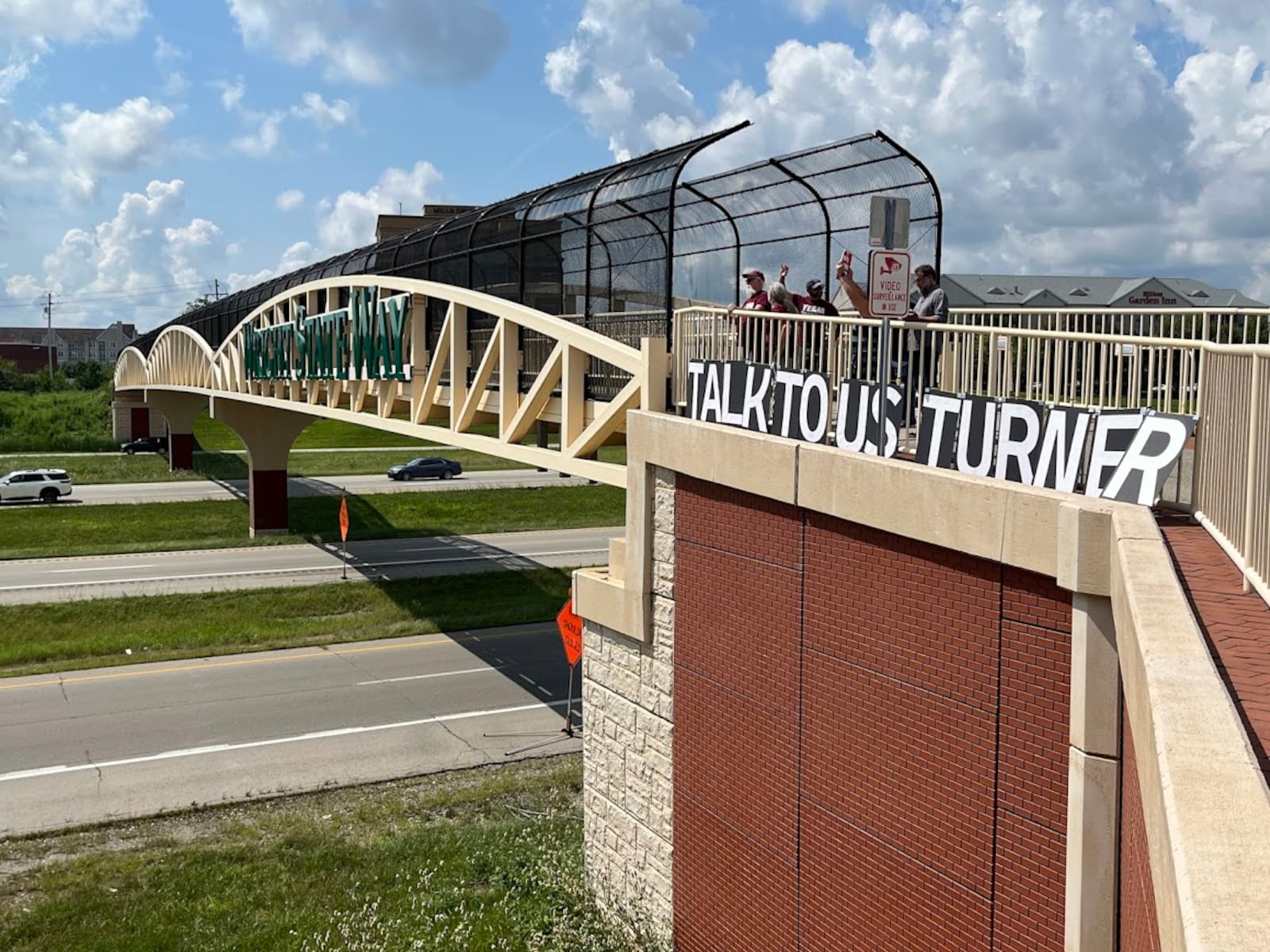 Protesters on the Wright State Way bridge over Interstate 675 in Fairborn on Aug. 7, 2025, with a sign urging U.S. Rep. Mike Turner, R-Dayton, to host public town hall meetings. THOMAS GNAU/STAFF