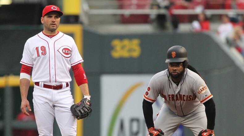 The Giants' Johnny Cueto, right, leads off in front of Reds first baseman Joey Votto on Monday, May 2, 2016, at Great American Ball Park in Cincinnati. David Jablonski/Staff