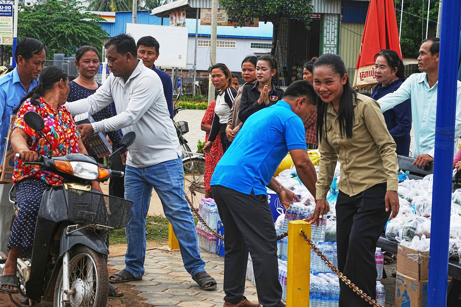 A Cambodian youth volunteer Chhar Sin, front right, welcomes villagers who donate their personal belongings for the displacing people at a sidewalk in Srey Snam district in Siem Reap province, Cambodia, Saturday, July 26, 2025, as border fighting between Thailand and Cambodia entered its third day, heightening fears of an extended conflict. (AP Photo/Heng Sinith)