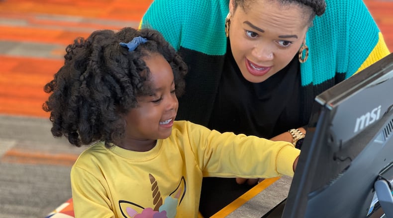 Chrissy Sanders and her daughter, Olivia, try out the technology at the new Dayton Metro Library Northmont Branch on Saturday. Chrissy serves as DML's finance director. AIMEE HANCOCK/STAFF