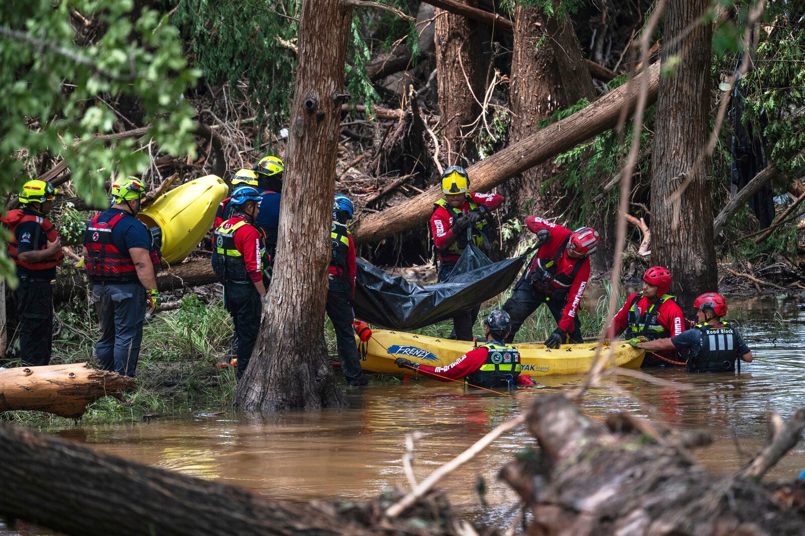 FILE - Firefighters from Ciudad Acuña, Mexico, load a body into a raft as they prepare for a water recovery along the Guadalupe River days after a flash flood swept through the area July 7, 2025, in Ingram, Texas. (AP Photo/Eli Hartman, File)