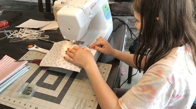 Brooklyn Work, 11, of Lebanon Schools has helped her mother Christine a Mason Schools teacher sew together hundreds of protective masks, distributed free to area communities. The masks are not medical grade but are created at the family s sewing machine and crafted together according to material and health guidelines provided by Warren County emergency officials. (Provided Photo/Journal-News)