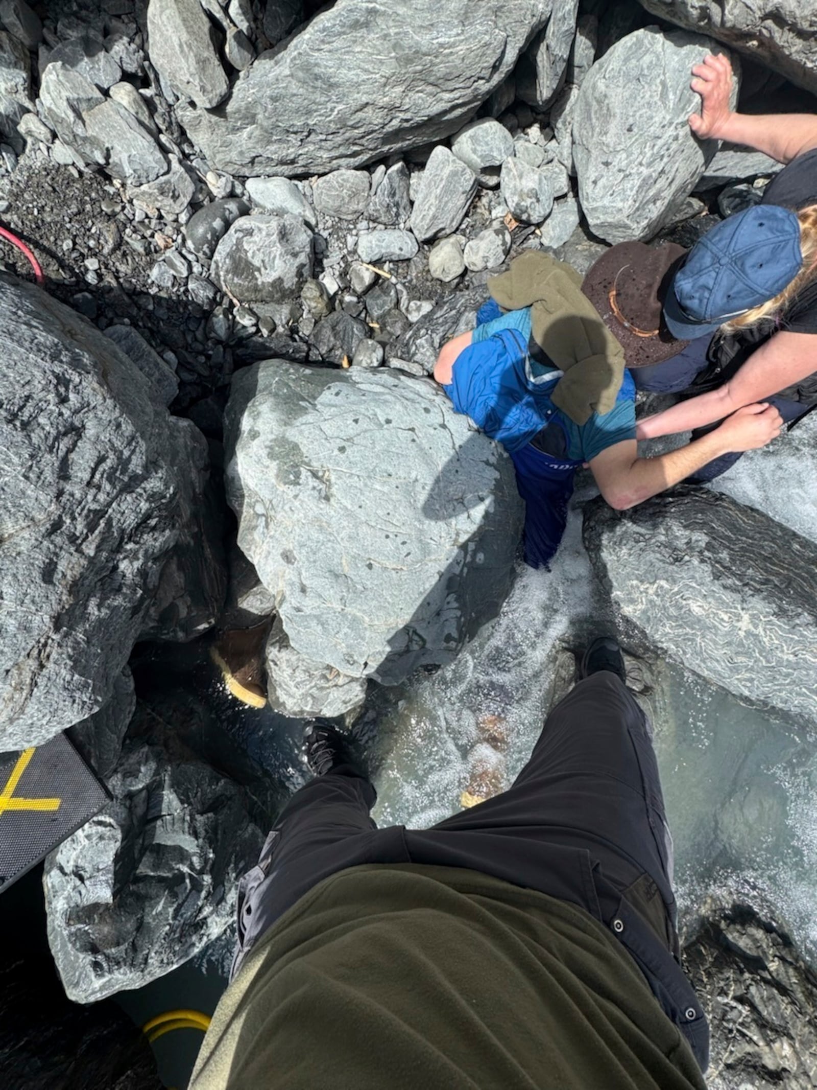 This May 24, 2025, photo shows Kell Morris, upper right in a brown hat, trapped under a 700 pound rock near Seward, Alaska. (Jason Harrington/Seward Fire Department via AP)