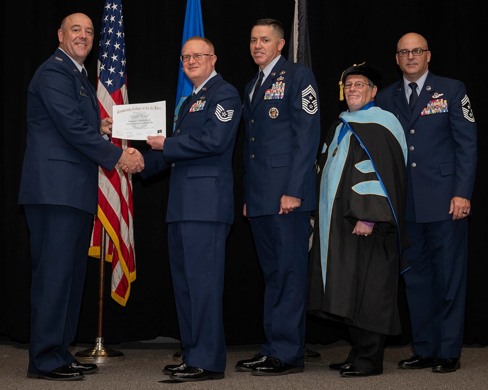 Col. Patrick Miller, 88th Air Base Wing and installation commander, presents Tech. Sgt. Christopher Tracy with his associate in applied science degree in information systems technology during the Community College of the Air Force graduation ceremony on June 15 at the National Museum of the Air Force. With Miller were Jason Schaffer, 88 ABW command chief; Donald Ellwood, CCAF Education Services director; and Chief Master Sgt. James Fitch, Air Force Research Laboratory command chief; who gave the commencement address. U.S. AIR FORCE PHOTO/R.J. ORIEZ