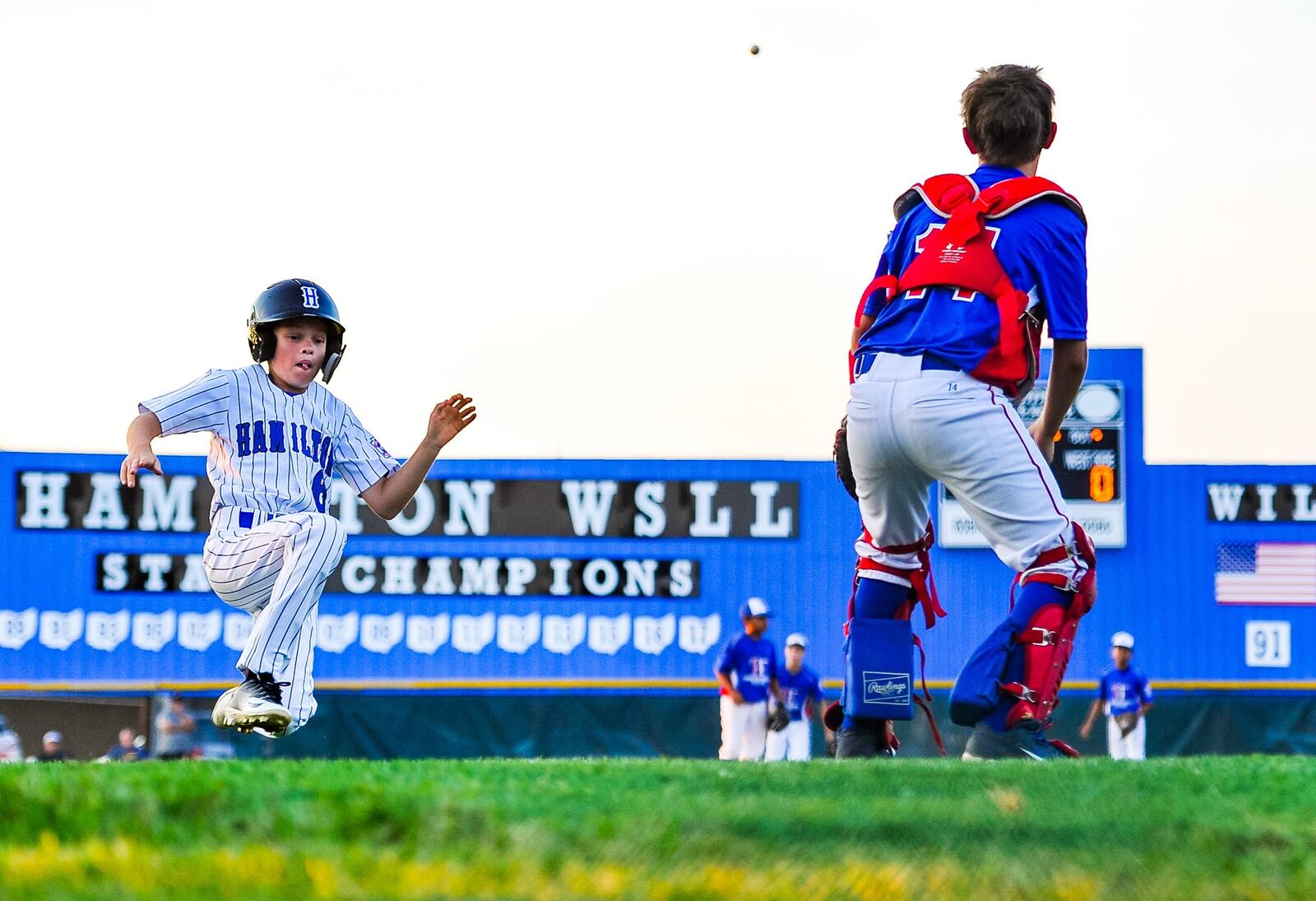 Hamilton West Side’s Sam Floyd slides into home plate for a first-inning run during Thursday night’s 15-0 win over Hamilton-Fairfield in Little League District 9 championship game at West Side. NICK GRAHAM/STAFF