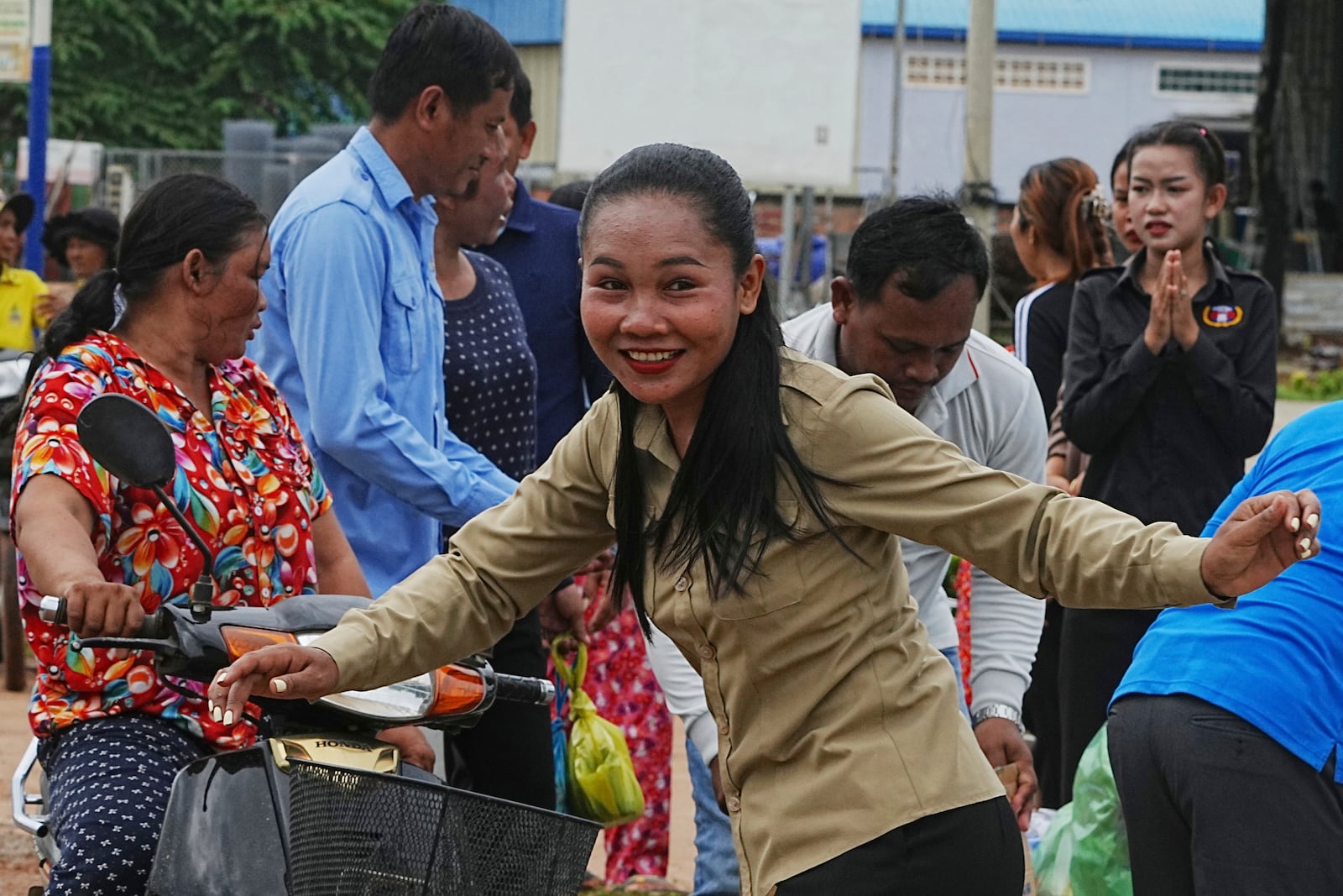 A Cambodian youth volunteer Chhar Sin, foreground, greats villagers who donate their personal belongings for the displacing people at a sidewalk in Srey Snam district in Siem Reap province, Cambodia, Saturday, July 26, 2025, during fighting between Thailand and Cambodia. (AP Photo/Heng Sinith)