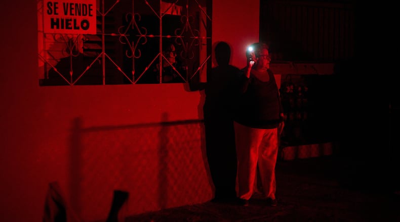Women use a cell phone flashlight as they chat through a window during a scheduled power outage as part of energy rationing in Santa Cruz del Norte, home to one of Cuba’s largest thermoelectric plants, late Tuesday, Feb. 3, 2026. (AP Photo/Ramon Espinosa)