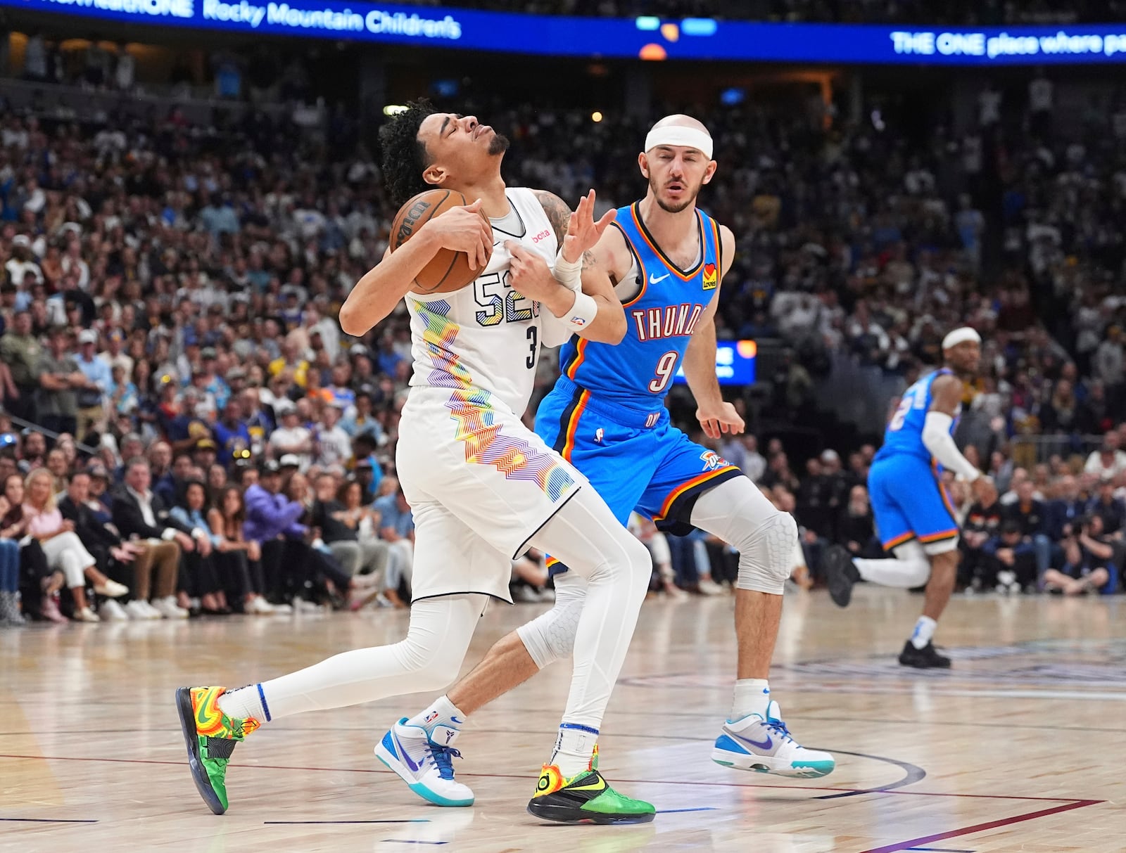 Denver Nuggets guard Julian Strawther, front, is fouled by Oklahoma City Thunder guard Alex Caruso in the second half of Game 6 in the Western Conference semifinals of the NBA basketball playoffs Thursday, May 15, 2025, in Denver. (AP Photo/David Zalubowski)