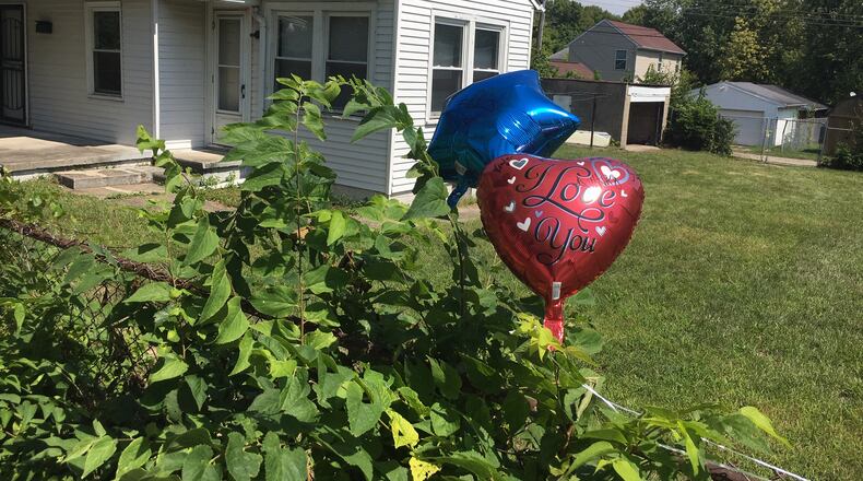 Balloons tied to the fence commemorate the lives of two teenagers killed on Conners Street on Wednesday night. STAFF