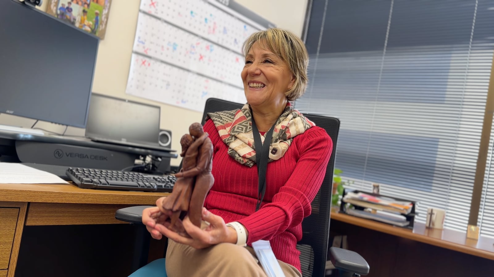 Martha-Jeannette Rodriguez holds up one of her works of art while sitting in her Welcome Dayton office. DAVID SHERMAN/STAFF