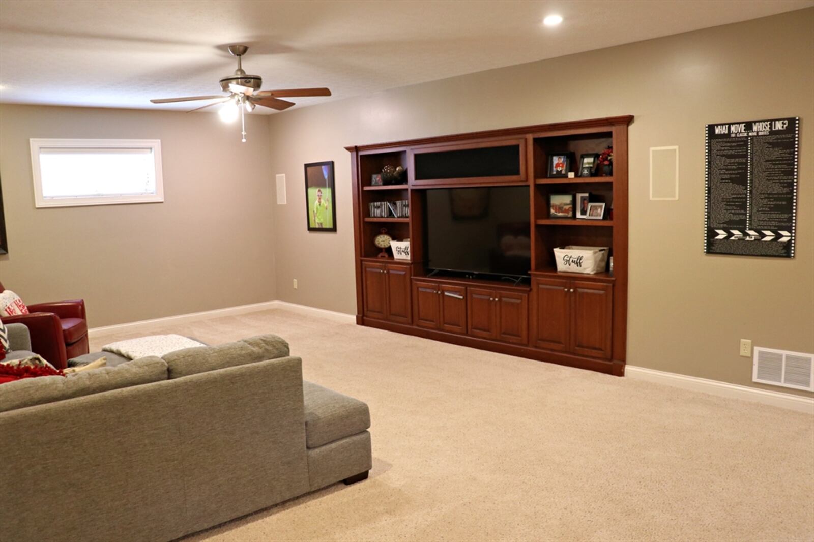 Along one wall in the lower level, a built-in media area includes open shelves and cabinetry. 