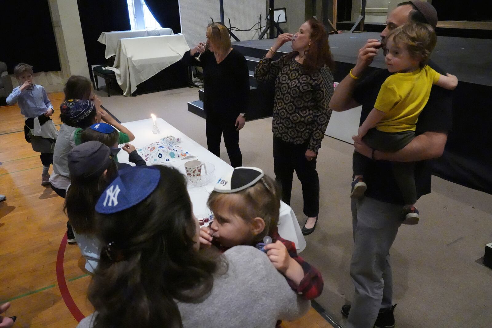Cantor Ruth Berman Harris, top center, who leads the congregation in lieu of a full-time rabbi, celebrates Seder with by drinking juice with children of the Pasadena Jewish Temple and Center which burned down in the Eaton fire, at the First United Methodist Church in Pasadena, Calif., Friday, April 4, 2025. (AP Photo/Damian Dovarganes)