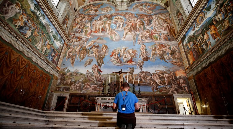 FILE - A visitor kneels in front of the Last Judgement fresco by the Italian Renaissance painter Michelangelo inside the Sistine Chapel in Rome, May 3, 2021. (AP Photo/Alessandra Tarantino, File)