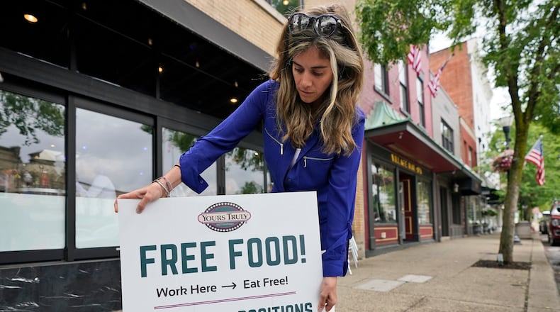 Coleen Piteo, director of marketing at Yours Truly restaurant, puts out a sign for hiring, Thursday, June 3, 2021, in Chagrin Falls, Ohio. The number of Americans seeking unemployment benefits fell last week for a fifth straight week to a new pandemic low, the latest evidence that the U.S. job market is regaining its health as the economy further reopens. (AP Photo/Tony Dejak)