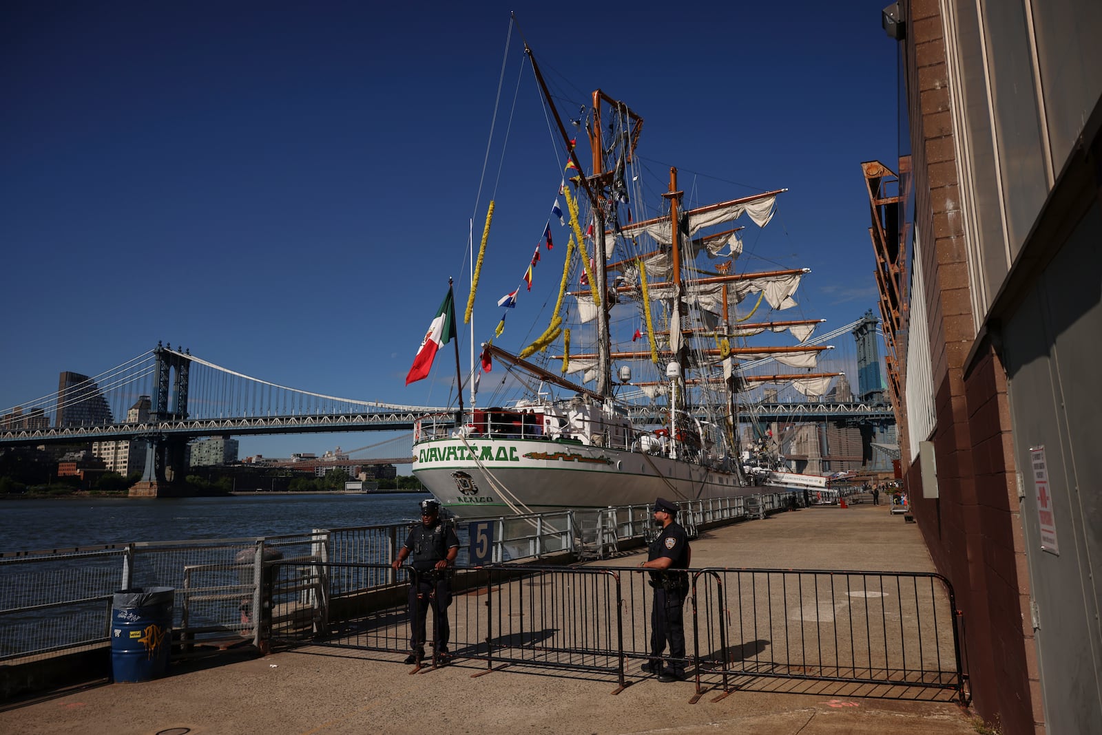 New York Police officers stands watch on Pier 35 where the Cuauhtémoc, a masted Mexican Navy training ship that collided with the Brooklyn Bridge the night before, sits docked. (AP Photo/Yuki Iwamura)