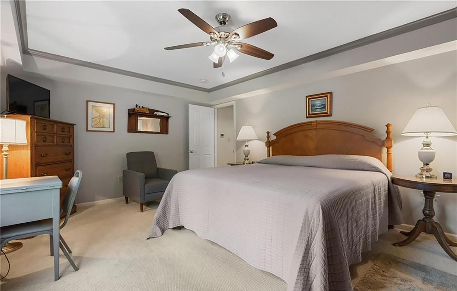 The primary bedroom has a tray ceiling, ceiling fan and neutral carpeting. CONTRIBUTED