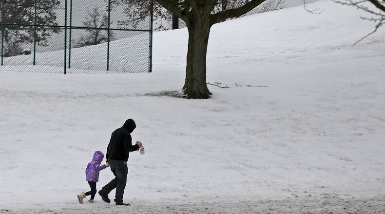 A man and little girl trudge through the snow along East Main Street in Springfield. BILL LACKEY/STAFF